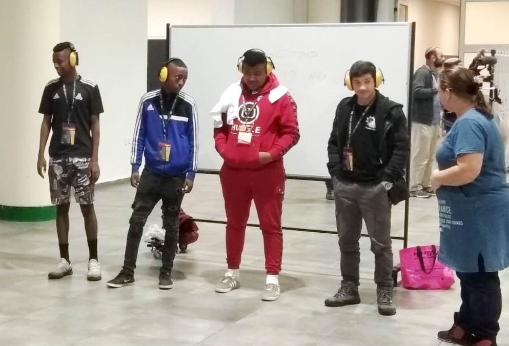 Youth wear headphones to experience what it is like to be hearing-impaired.
